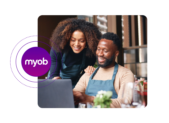 two employees looking on a computer and smiling with myob logo